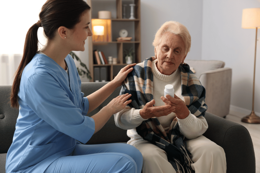 A caretaker helping an elderly woman with medication
